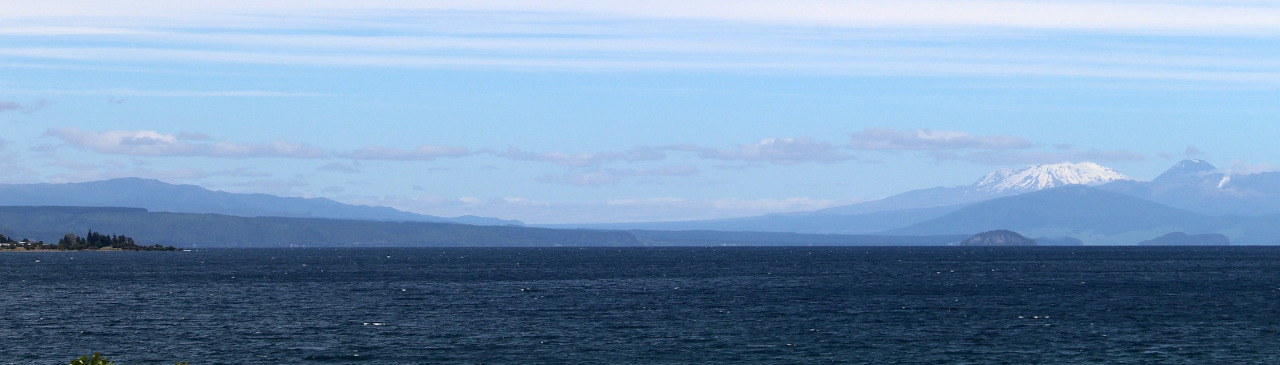 Ufer des Taupo Sees mit Bergen im Hintergrund